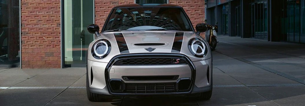 A front view of the MINI Hardtop 2 Door parked in front of a brick building