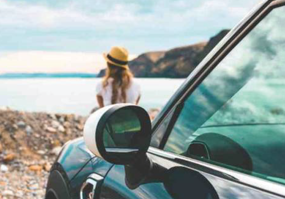 Woman sitting in front of a MINI next to the ocean